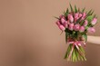 © New Africa - Woman with bouquet of beautiful tulips on dark beige background, closeup. Space for text