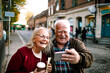 © Davor - Happy senior couple taking selfie while walking in city street on vacation