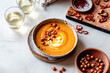 © The Picture Pantry - A bowl of creamy Carrot soup garnished with sliced peppers and crunchy snacks, accompanied by two glasses of sparkling beverage.