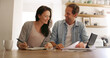 © BuyoutReese10/peopleimages.com - Home, documents and couple with smile, finance and payment for mortgage, tablet and conversation Apartment, banking and man with woman in kitchen, investment and discussion with savings growth