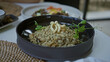 © Krakenimages.com - Woman enjoying mediterranean meal in restaurant featuring mushroom risotto with pea shoots and pasta garnish, capturing a dining experience indoors with focus on culinary details.