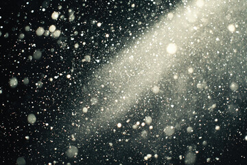 Poster - Abstract image of glittering particles and bokeh lights in dark background, resembling snowfall or stardust.