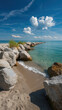 © MasTPX - Serene ocean view featu a rocky breakwater stretching into the turquoise sea under a sunny blue sky dotted with fluffy white clouds in the summer sunlight.