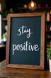 © Artem Zatsepilin - motivational message 'stay positive' written on black chalkboard with wooden frame, placed on wooden table. inspiration and positivity theme. office, cafe, home decor.