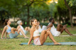 © JackF - Fit young girl enjoying yoga session on green glade in sunlit summer park with group of enthusiasts, embracing fitness and relaxation in nature..