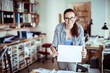 © Geber86 - Young woman holding a blank piece of paper in a startup company office with copy space