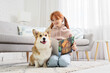 © Pixel-Shot - Teenage redhead girl with cute Corgi dog reading story on carpet at home