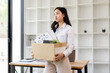 © David - Business woman with box cardboard packing personal items after losing jobs. asian business woman standing on office background. Your fired Unemployed Jobless People Crisis