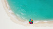 © NN AI - Aerial view of colorful beach umbrella on pristine white sand with turquoise ocean waves. Summer vacation paradise. Tropical holiday destination. Travel from above. Seaside relaxation spot. Tourism