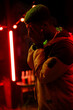 © fotofabrika - Emotional moment captured at night in a vibrant urban setting with red lights and a contemplative figure