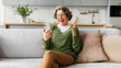 © Home-stock - Amazed happy senior woman holding smartphone, using mobile app, receiving gift, reading good sms, sitting on couch at home, panorama