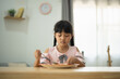 © WMSTUDIO - Young Girl Enjoying Breakfast in Bright Kitchen, Focused on Plate Surrounded by Natural Light, Indoor Dining Scene with Soft Decor and Calm Atmosphere