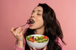 © Nataliya - Young brunette snacking on a portion of a vegetarian dish with her eyes closed in front of the camera. Healthy food concept