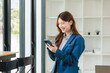 © Kritdanai - Smiling Asian Businesswoman Using Smartphone in Office