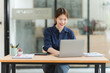 © Kritdanai - Smiling Woman Working at Desk with Laptop