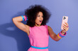 © deagreez - Young woman in pink dress taking a selfie with surprised expression against a purple studio background