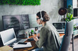© deagreez - Young female programmer working at office desk with multiple screens, wearing casual attire, focused on coding and programming