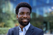 © Liubomir - Successful African American businessman outside office building, smiling happily to the side. Man in business suit close-up.