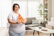 © Ljupco Smokovski - Corpulent woman holding a slice of pepperoni pizza