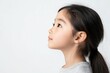 © jayantha - A young girl with dark hair in a ponytail looks to the side, her expression thoughtful and serene.