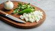 © THIBNH - Green chilli pepper and onion slices with a knife on chopping board.