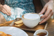 © Vladimir Razgulyaev - Enjoying a warm cup of coffee with biscuits in a cozy cafe during a sunny afternoon Cappuccino mug in a woman's hand on a wooden table, morning coffee.