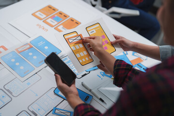 Wall Mural - web designers are comparing a paper prototype of a mobile application with a smartphone, improving u