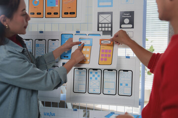 Wall Mural - two web designers are discussing user interface and user experience of a mobile application, attachi