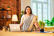 © StockImageFactory - Indian woman boss gives thumbs up and smiles while standing near laptop at office desk