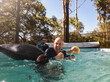 © Austockphoto - Man in his fifties playing with kids and grandchild in backyard pool in summer laughing out loud