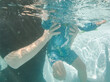 © Austockphoto - underwater view of man helping toddler kid swim through water in pool