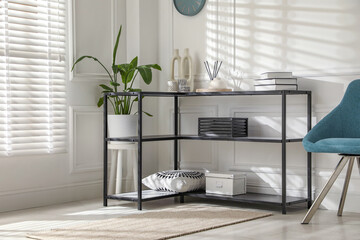 Poster - Console table with different decor and chair near white wall indoors. Interior design