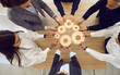© Studio Romantic - Entrepreneurs, office workers or business partners stacking wooden gears next to each other, symbolizing development and success. Concept of teamwork and business cooperation. Top view.