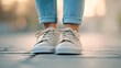 © Wannapha - Casual footwear on a young adult, close-up of white sneakers on a sunny sidewalk, vibrant urban environment, stylish and relaxed.