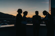 © qunica.com - Silhouetted business people are seen shaking hands on a rooftop at sunset, symbolizing connection and partnership. The setting sun adds a dramatic and inspirational backdrop to the corporate