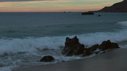 Wall Mural - Golden sunset on a beach, foamy waves rolling towards white sand beach under low the sun light