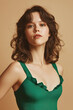 © Klay - confident young woman posing in stylish green ruffled swimsuit against soft beige background fashion portrait for summer lifestyle concept