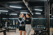 © qunica.com - Two women embrace and high-five each other in a gym setting, exuding friendship and mutual support during their fitness journey.
