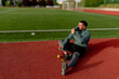 © we.bond.creations - Male athlete resting on the running track, sipping water and recharging after an intense training session, embracing a healthy lifestyle