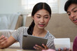 © itchaznong - Digital Finance and Cohabitation. A young couple engaging in financial discussions over a tablet, highlighting modern money management.