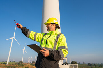 Wall Mural - engineer wearing uniform inspection and survey work in wind turbine farms rotation to generate elect