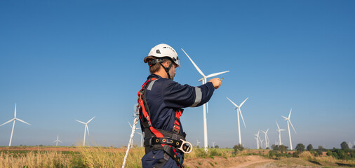 Wall Mural - engineer wearing uniform inspection and survey work in wind turbine farms rotation to generate elect