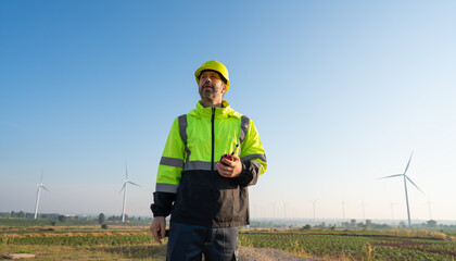 Wall Mural - engineer wearing uniform inspection and survey work in wind turbine farms rotation to generate elect