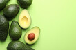 © New Africa - Whole and cut avocados on light green background, flat lay. Space for text