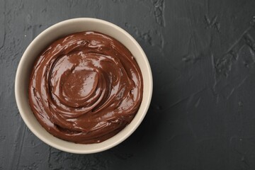 Wall Mural - tasty chocolate pudding in bowl on black table, top view. space for text