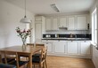 © Muaz - Bright kitchen with wooden table and chairs flowers in vase white cabinets and black countertops