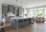 A modern kitchen with gray cabinets island stools and a dining area with large windows and sunflowers