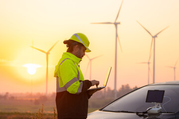 Aufkleber - Engineer working on laptop in front of wind turbines for checking wind turbines of the field during beautiful sunset. Alternative energy concept.