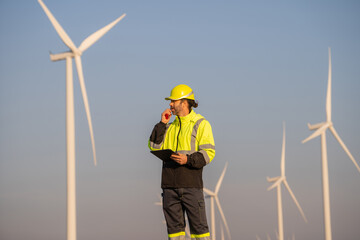 Fototapete - Engineer man working with tablet at windmill farm Generating electricity clean energy. Wind turbine farm generator by alternative green energy.