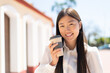 © luismolinero - Pretty Chinese woman at outdoors holding a take away coffee with happy expression